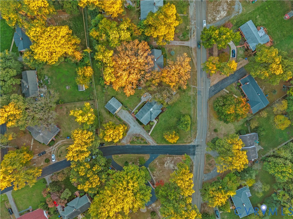Aerial perspective of a neighborhood featuring mature deciduous trees, paved roadways, residential lots, and established landscaping