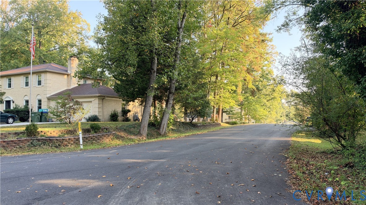 Two-story residence featuring light-toned masonry exterior, attached garage, and mature trees situated on a paved road Two-story residence featuring light-toned masonry exterior, attached garage, and mature trees situated on a paved road