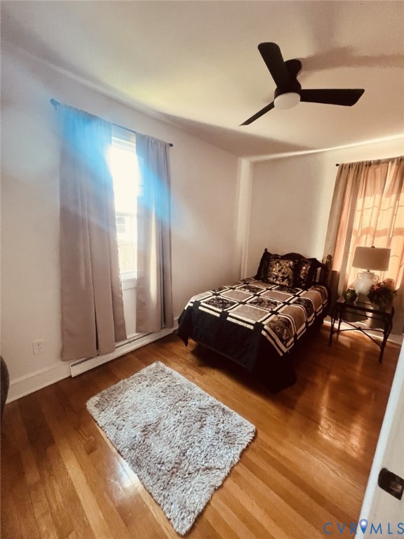 Wood-finish flooring, dual windows with natural light, and a modern three-blade ceiling fan