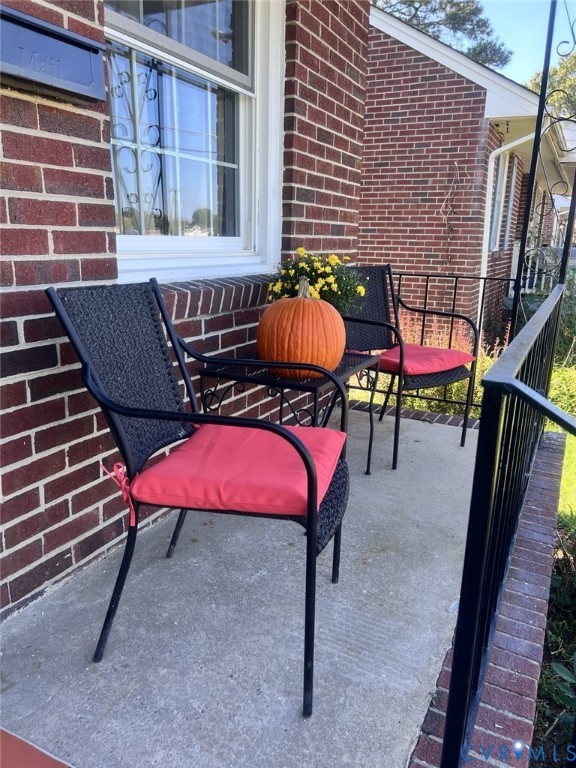 Red brick exterior featuring a concrete porch and black metal railings