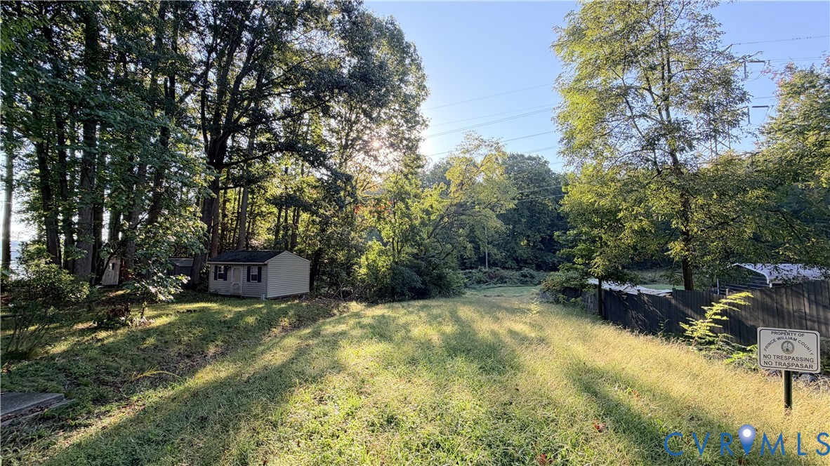 Expansive lot featuring mature trees, a detached storage structure, and perimeter wood fencing Expansive lot featuring mature trees, a detached storage structure, and perimeter wood fencing