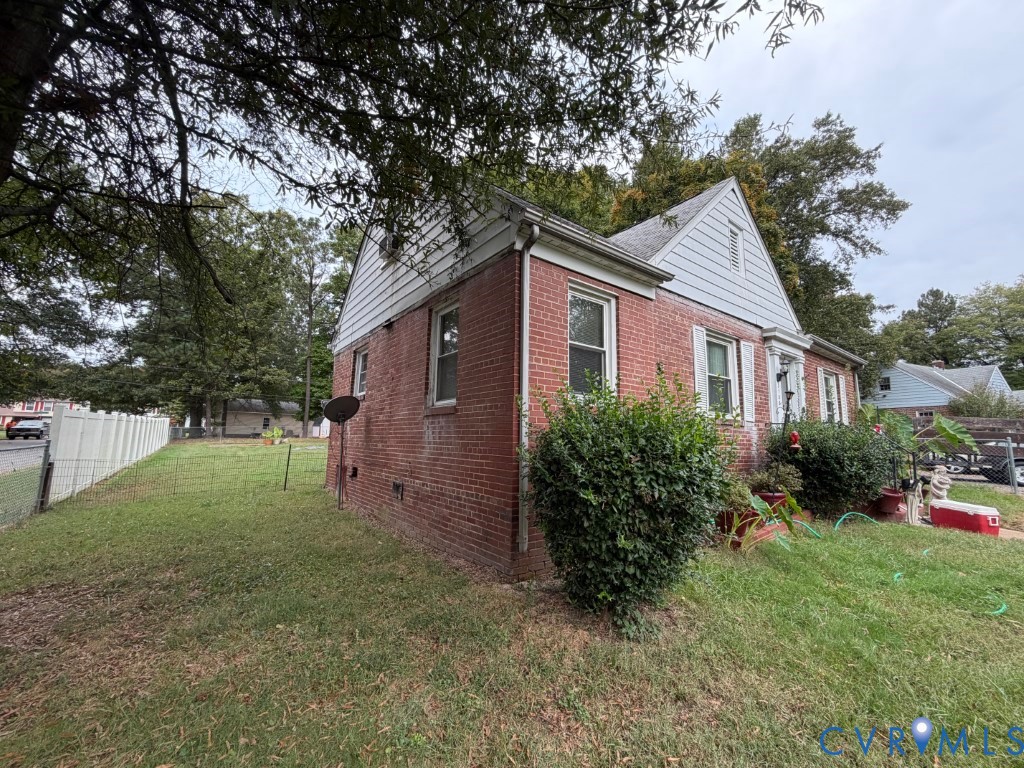 Brick exterior featuring white gable siding, double-hung windows, and a corner lot with white vinyl fencing
