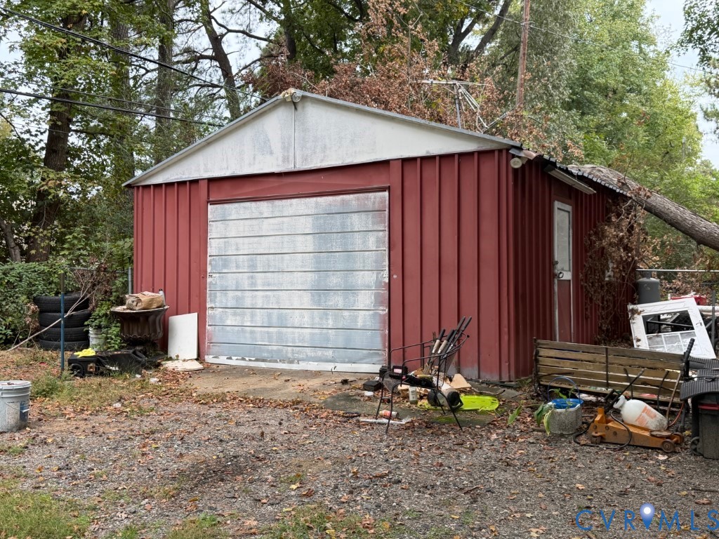 Detached storage structure featuring vertical metal siding, a gable roof, and a single-car rolling garage door