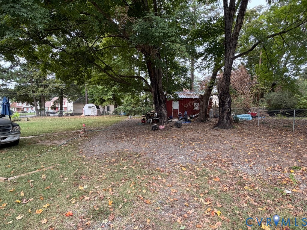 Expansive grounds featuring mature trees, partial chain-link fencing, and a detached structure
