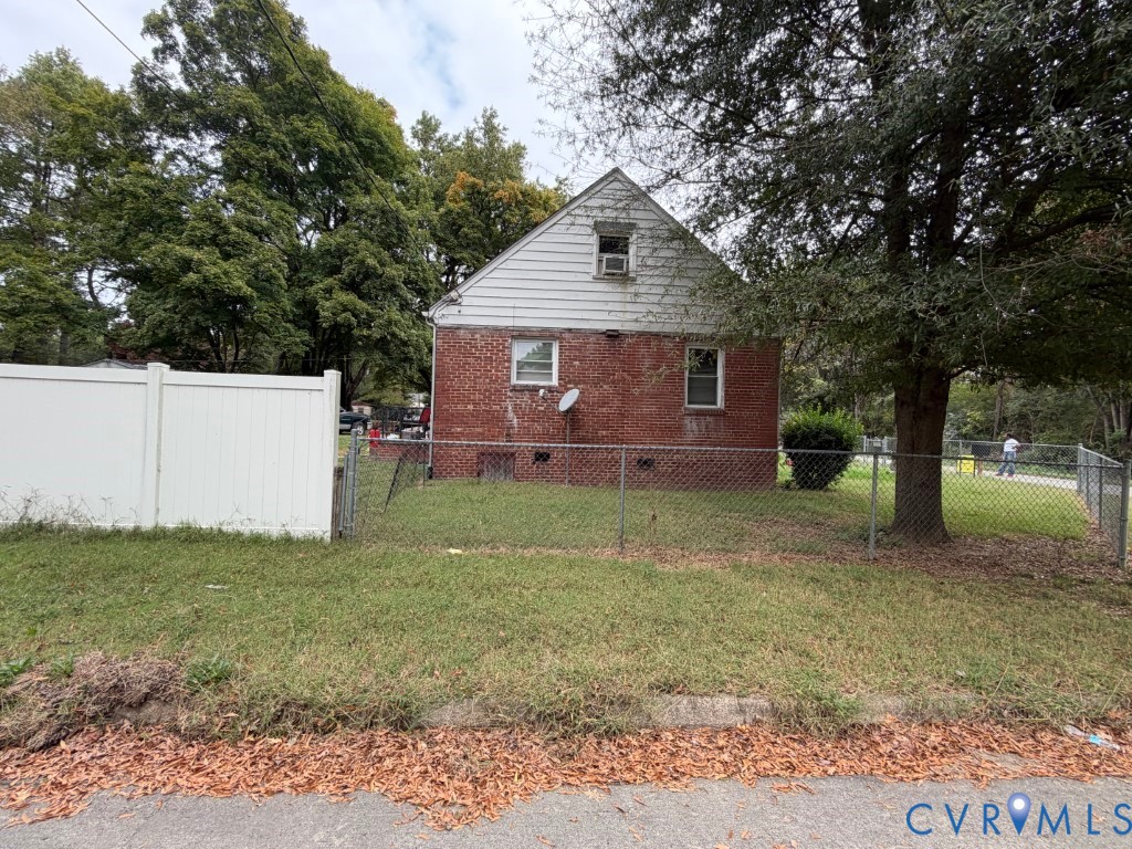 Exterior featuring a brick and horizontal siding faade with mature trees and perimeter fencing