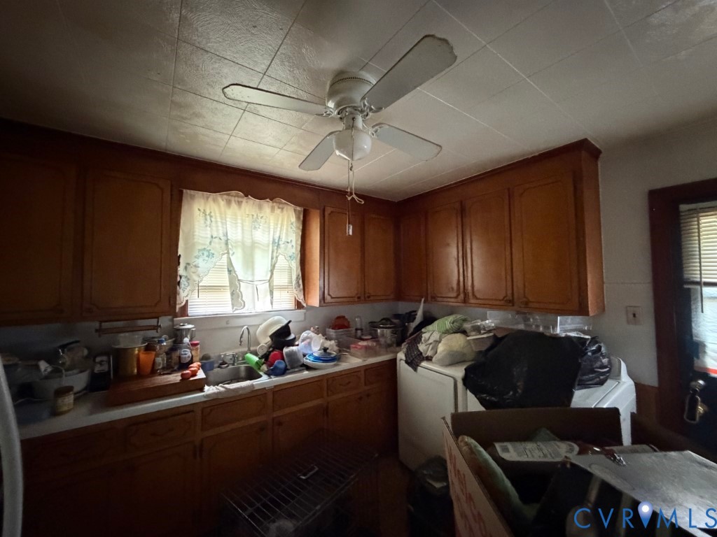 Kitchen featuring wood cabinetry, stainless steel sink, tile ceiling, and overhead ceiling fan