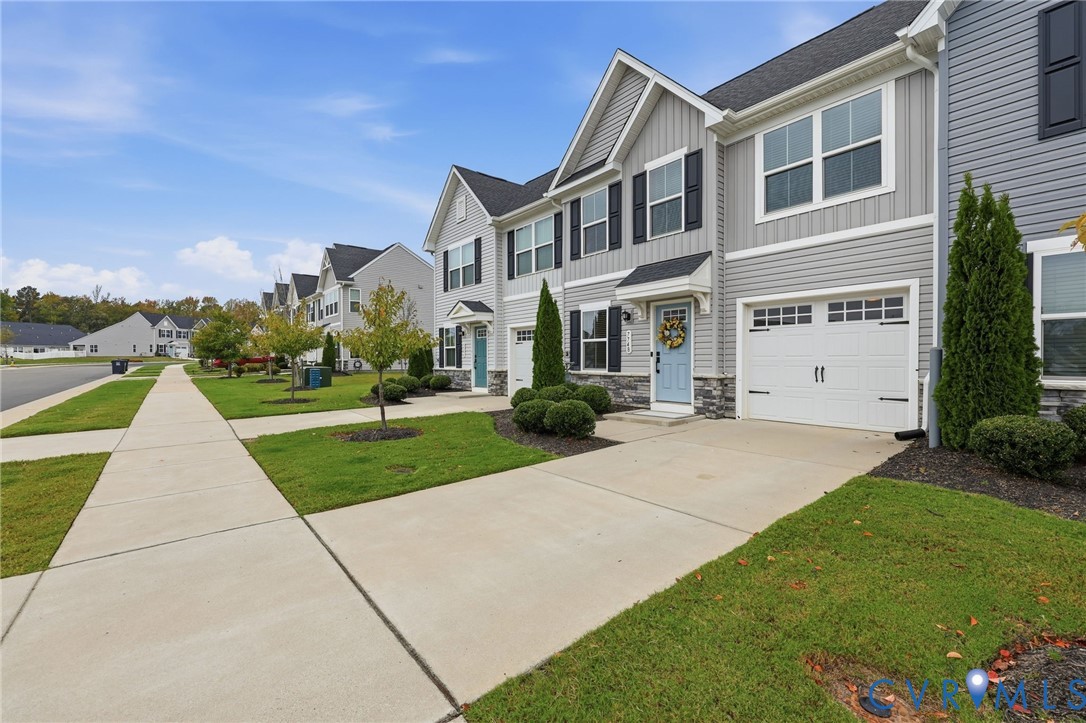Multi-story exterior featuring gray vinyl siding, stone veneer accents, an attached garage, and a concrete driveway Multi-story exterior featuring gray vinyl siding, stone veneer accents, an attached garage, and a concrete driveway