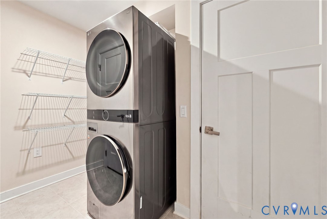 Stacked stainless steel laundry appliances, multi-tiered white wire shelving, and a solid-core three-panel interior door with brushed metal hardware