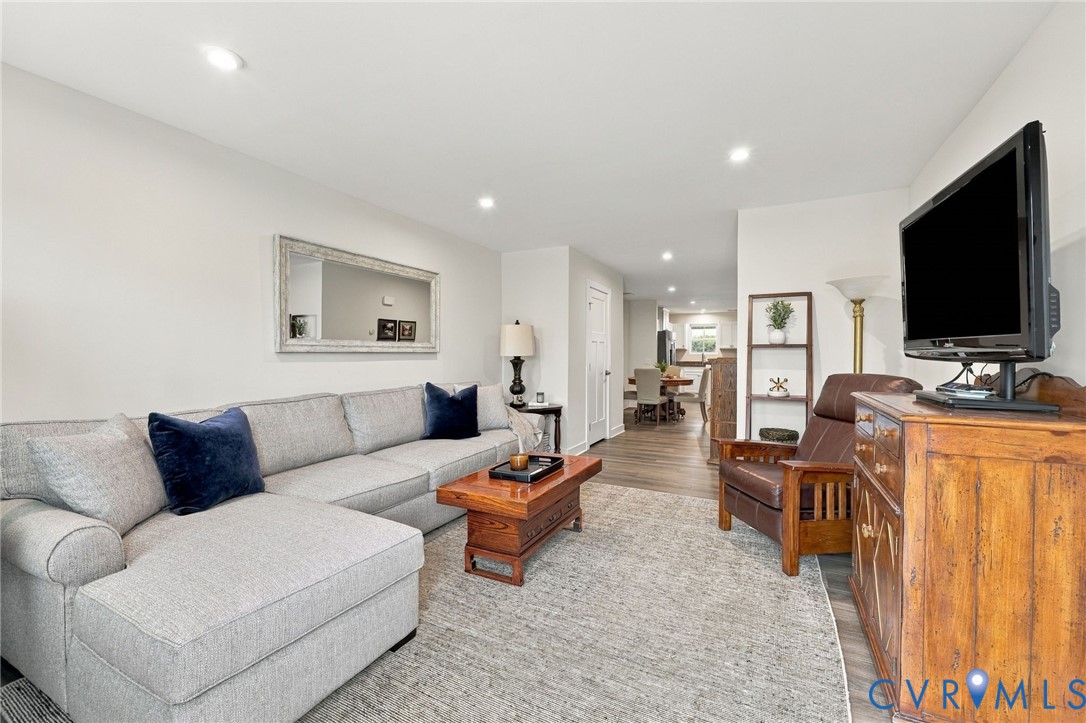 Neutral-toned interior space featuring recessed ceiling lighting, wood-finish flooring, and a wall-mounted rectangular mirror