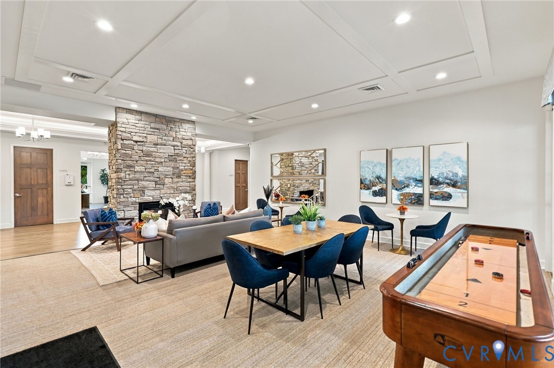 Expansive open-concept room featuring coffered ceilings, recessed lighting, a stone-faced accent wall, and wood-finish flooring