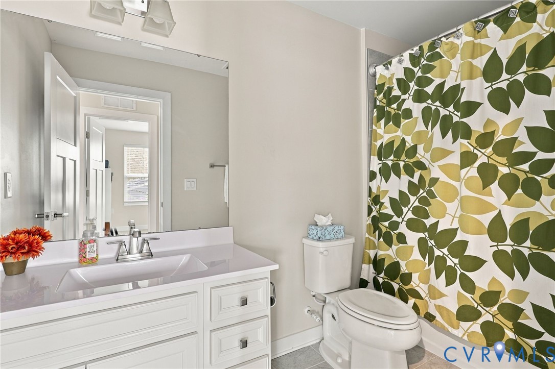 Bathroom featuring a white vanity cabinet, integrated sink with a chrome faucet, wall-mounted mirror, and a tub-shower combination
