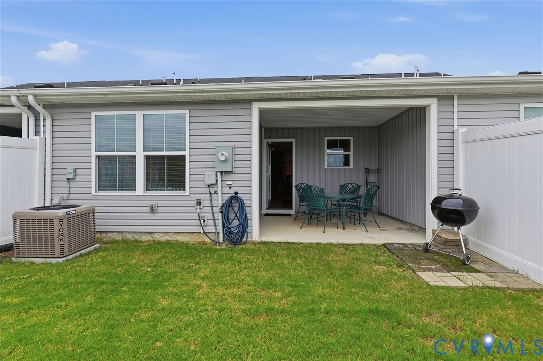 Covered concrete patio, light gray vinyl siding, and white vinyl privacy fencing