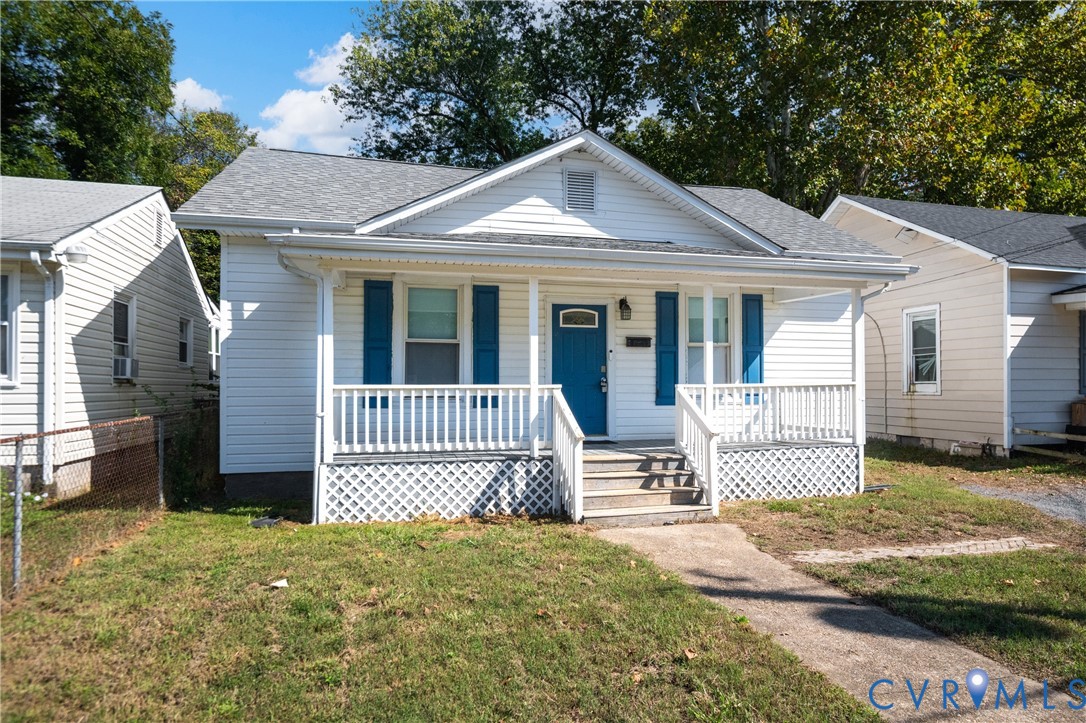 Single-story residence featuring white horizontal siding, blue shutters, a covered front porch with white railing, and decorative lattice skirting