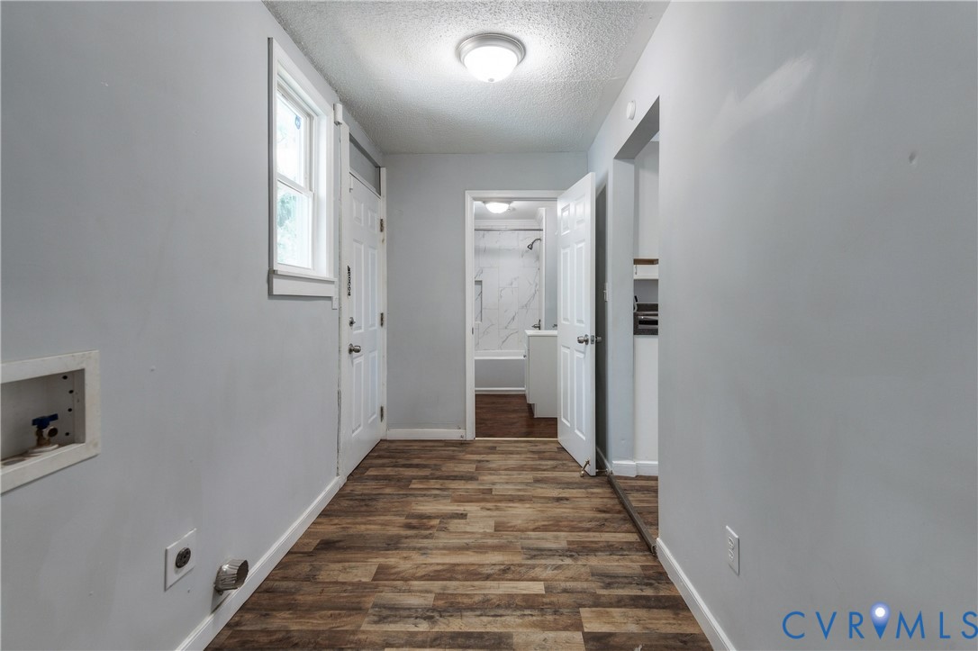Utility space featuring wood-finish flooring, a recessed laundry hookup station, a paneled door, and flush-mount ceiling lighting