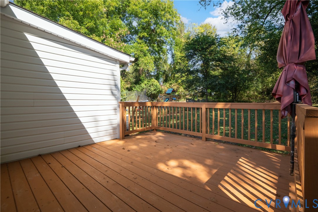 Raised wood-tone deck featuring a perimeter railing and light-toned horizontal siding