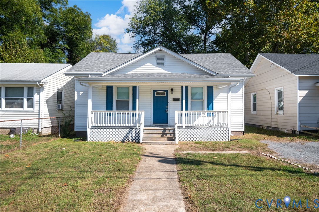 Gable-roof exterior with white siding, blue shutters, a covered front porch featuring a lattice base, and a central paneled door