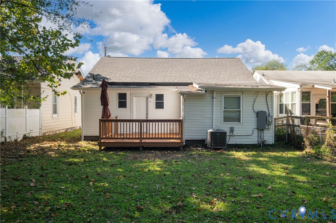 Rear exterior featuring white horizontal siding, a raised wood deck, a shingle roof, and a fenced backyard
