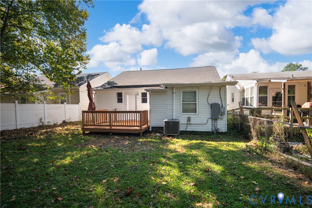 Rear exterior featuring white horizontal siding, a wood deck, and a white privacy fence