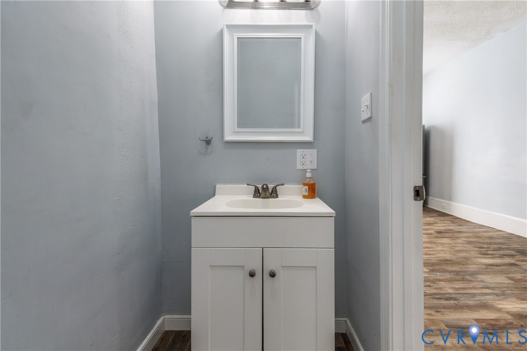 White vanity with an integrated countertop sink, two-handle faucet, framed wall mirror, and modern overhead light fixture