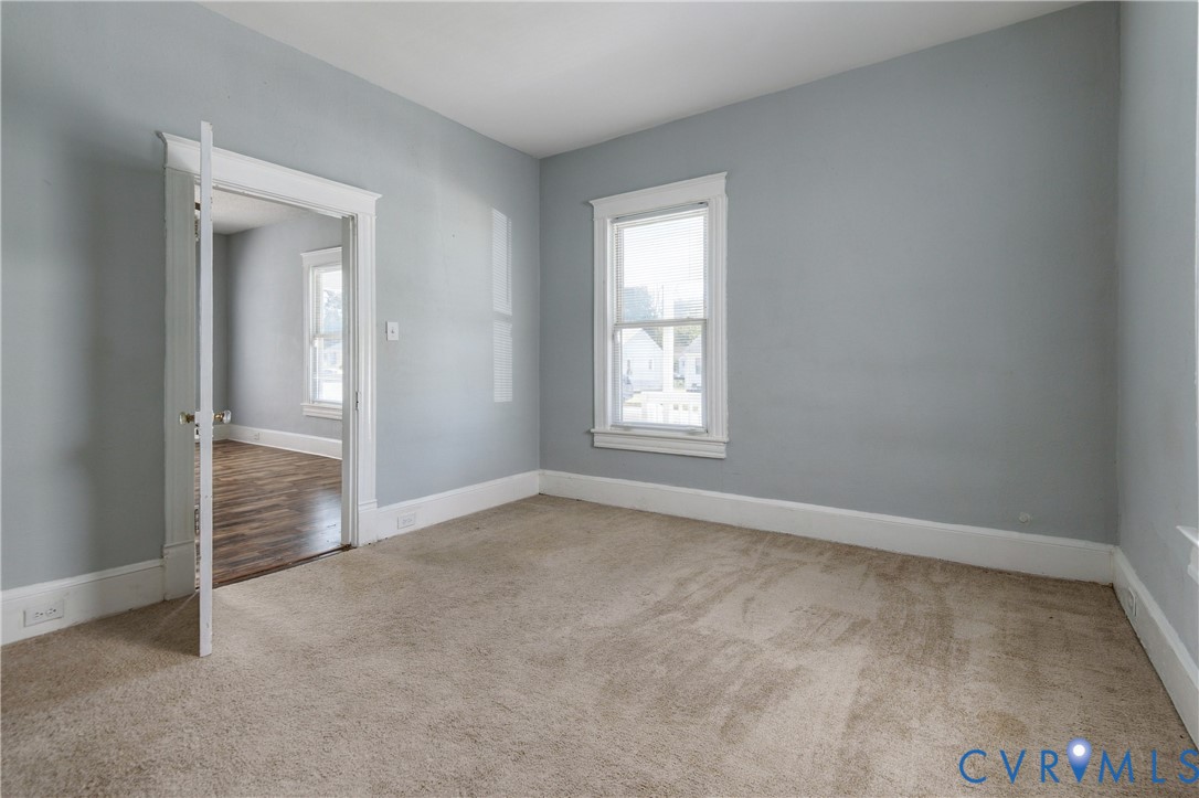 Room with neutral-toned carpeting, light grey walls, and white window casing