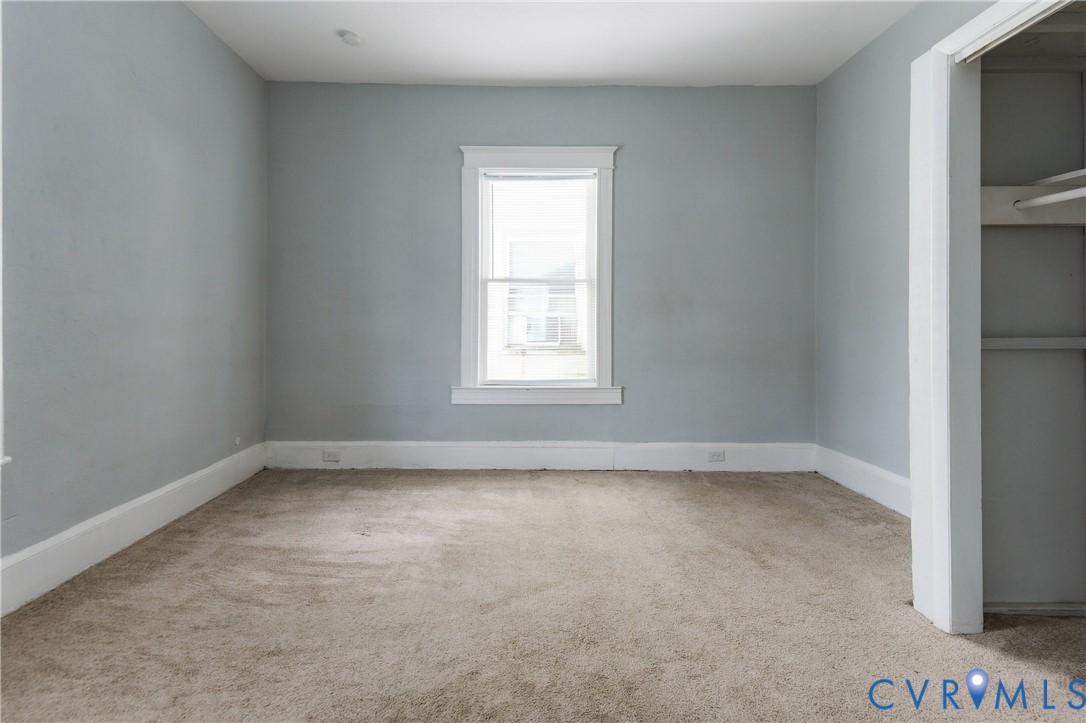 Neutral-toned wall paint, neutral carpeting, and a built-in closet with overhead shelving