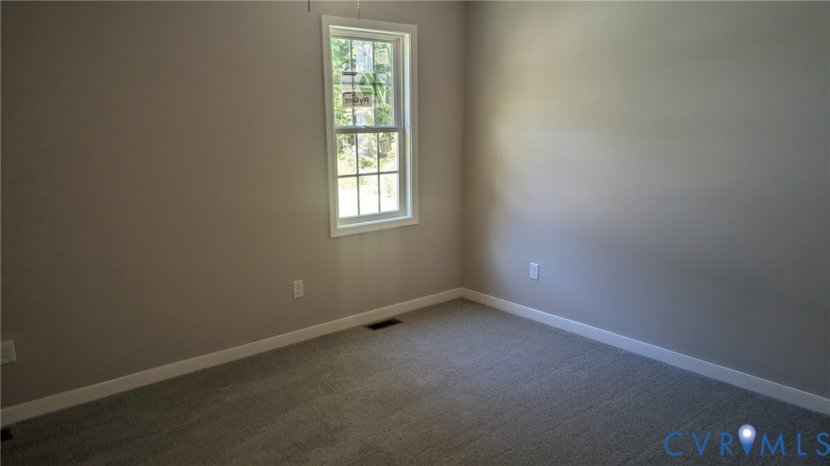 Neutral-toned walls, wall-to-wall carpeting, and a single-hung window with a grid pattern