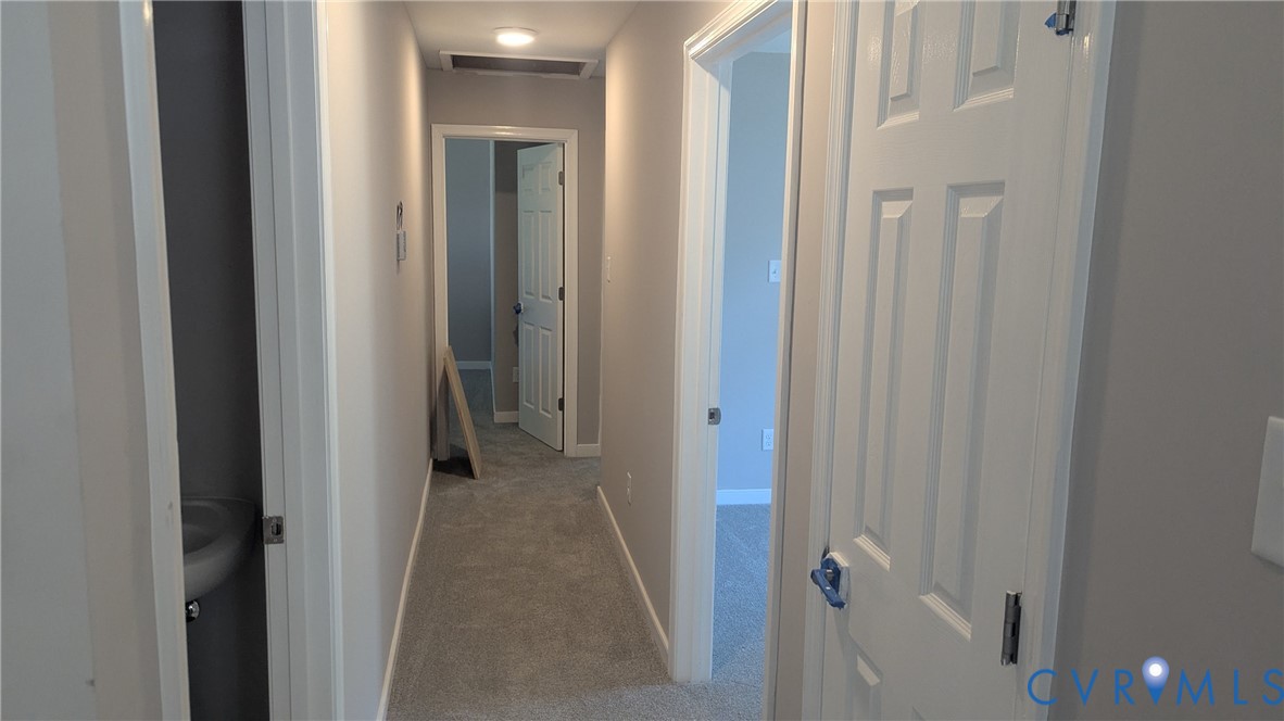 Interior hallway featuring wall-to-wall carpeting, neutral-toned walls, and multiple four-panel interior doors
