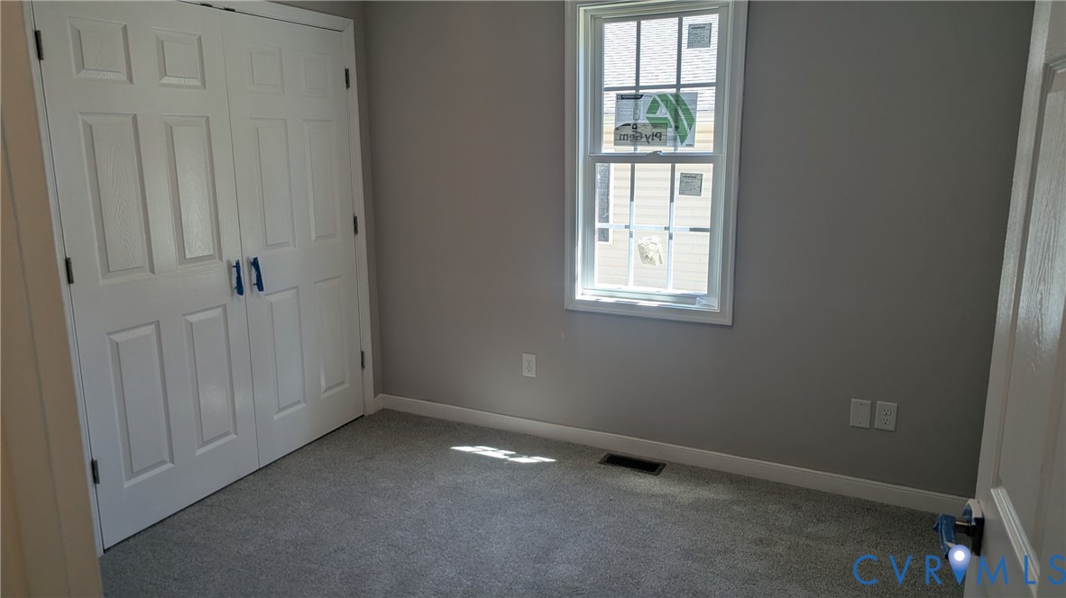 Neutral-toned room featuring wall-to-wall carpeting, dual-panel closet doors, and a single-hung window with a grille pattern