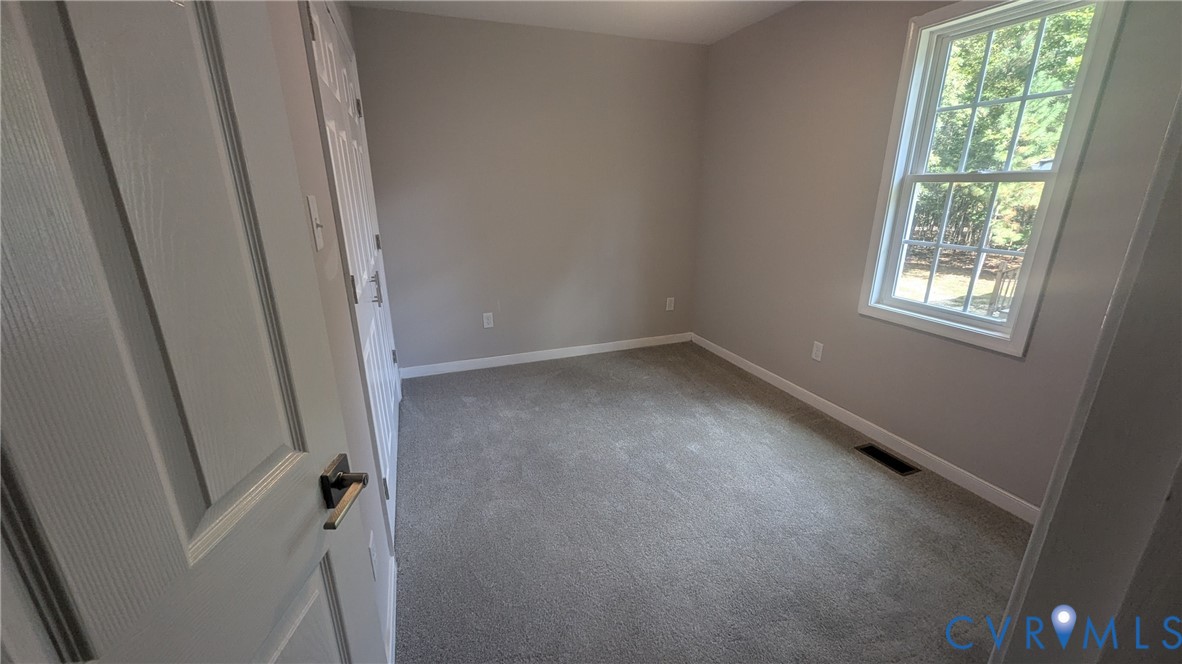 Neutral wall tones, wall-to-wall carpeting, a multi-pane window, and a multi-panel interior door with brushed metal hardware