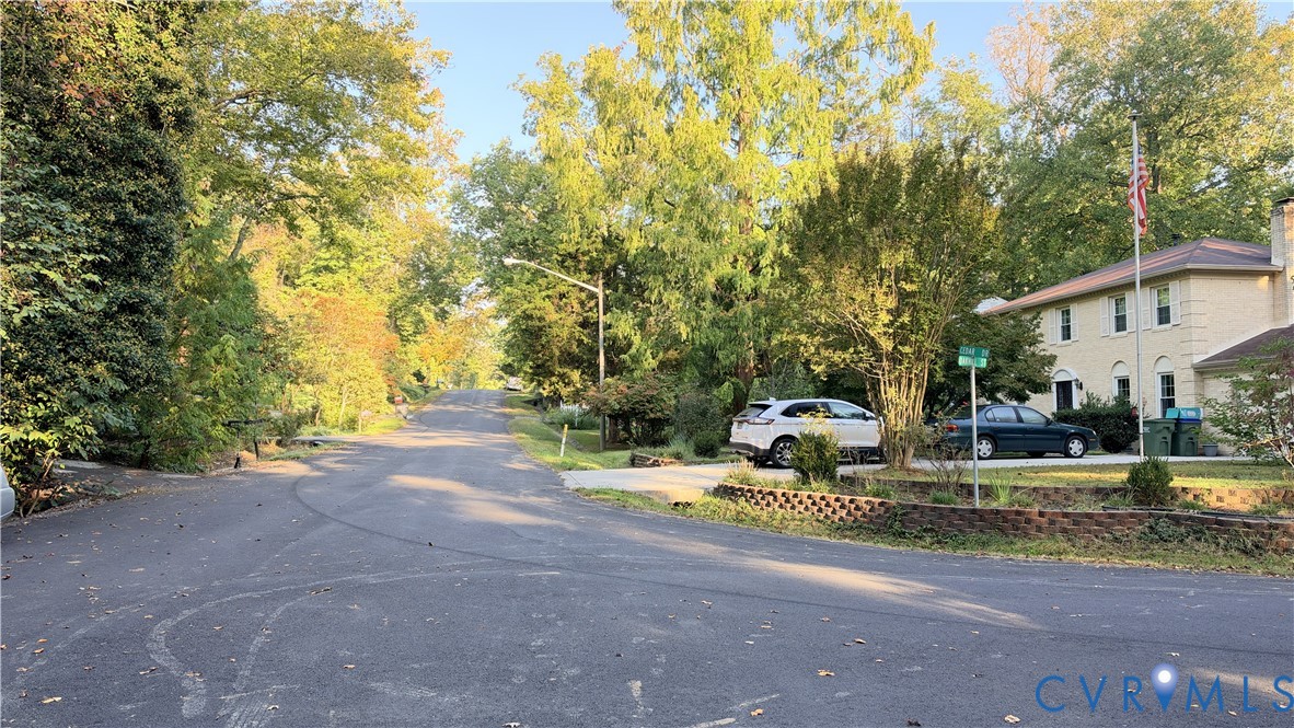 Light-colored masonry exterior featuring a multi-level roofline, concrete driveway, and mature perimeter trees Light-colored masonry exterior featuring a multi-level roofline, concrete driveway, and mature perimeter trees