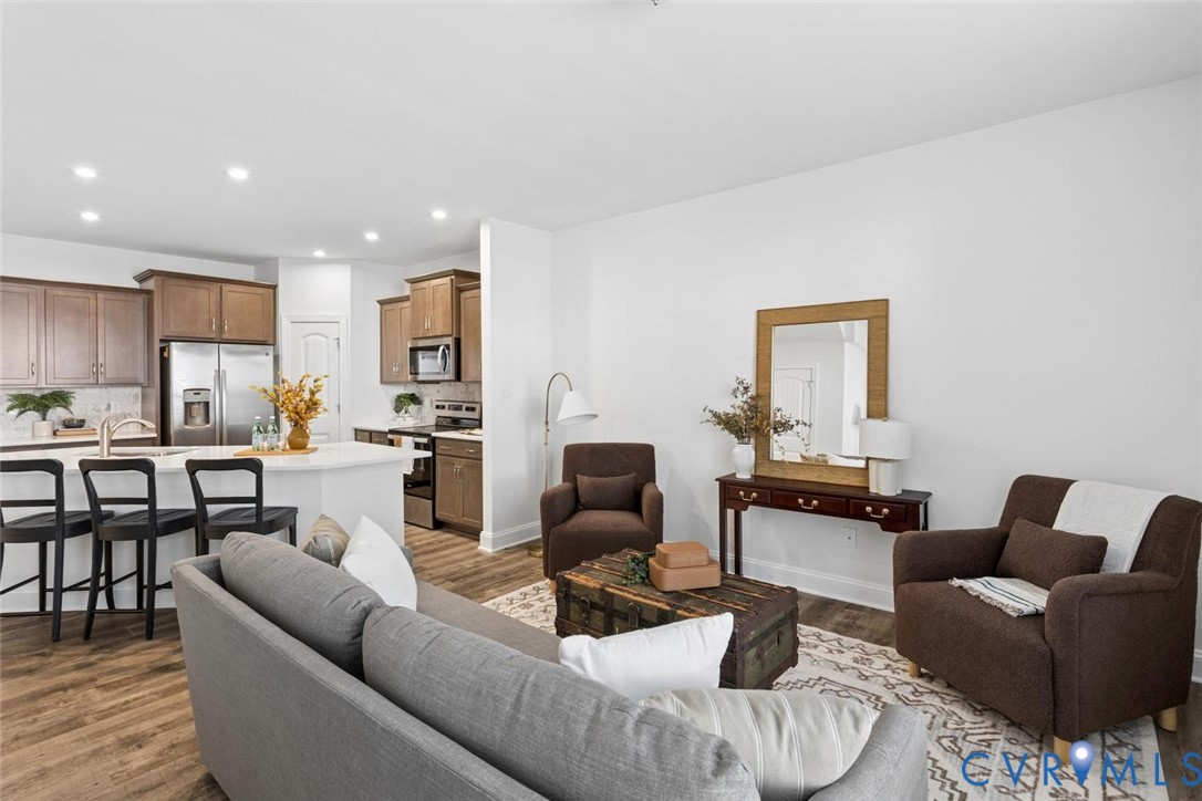Open-concept living area with LVP flooring, recessed lighting, and a white color palette.