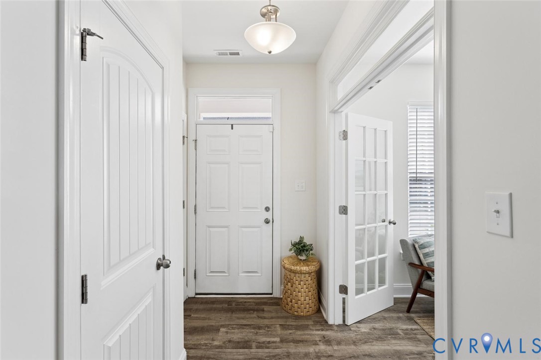 Entryway featuring LVP flooring, a six-panel exterior door with a transom window, and glass-paned French doors leading into the beautiful flex room.