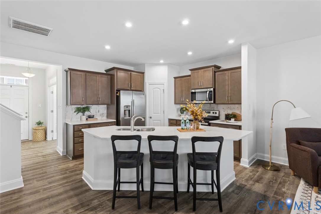 Expansive kitchen island with white quartz countertop, recessed lighting, and stainless steel appliances.