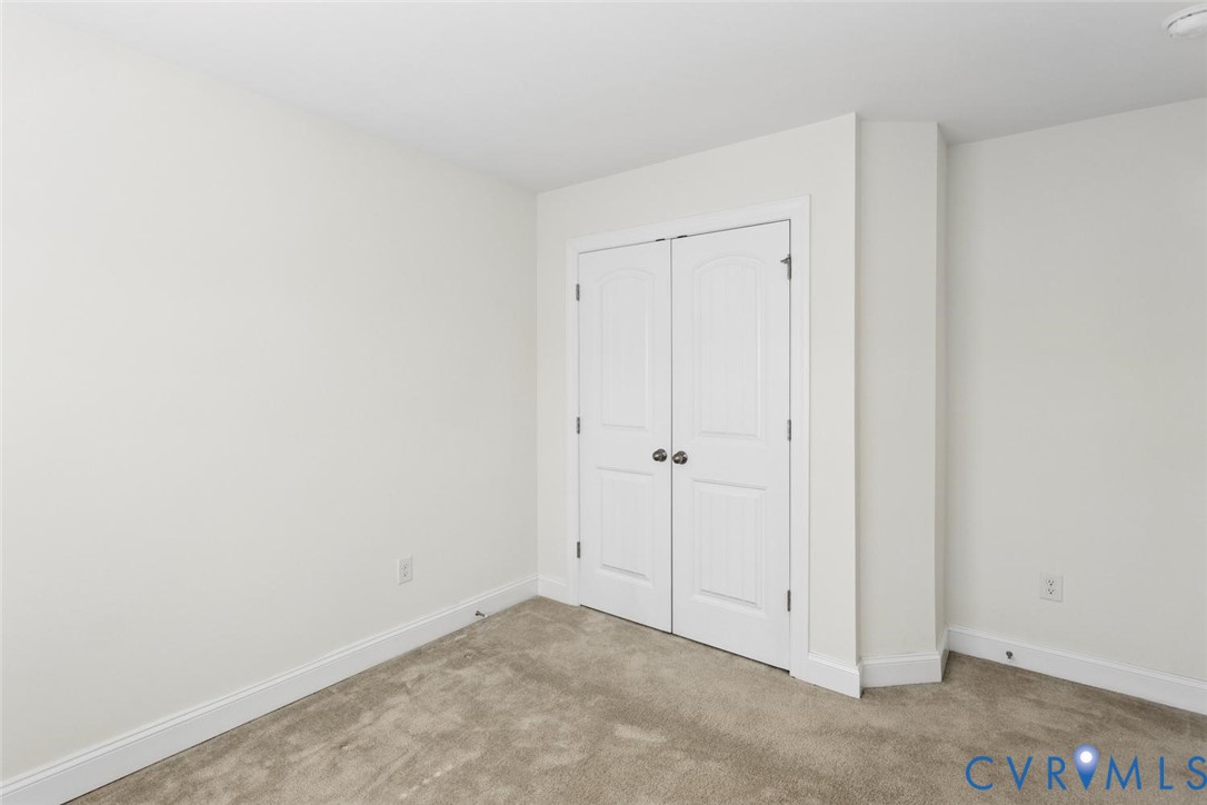 Neutral wall paint, carpet flooring, and white double closet doors