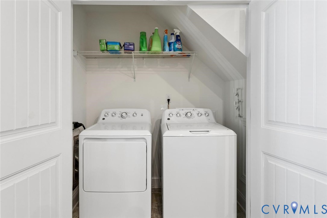 First Floor Laundry closet with white double doors, wire shelving, and an included washer and dryer.