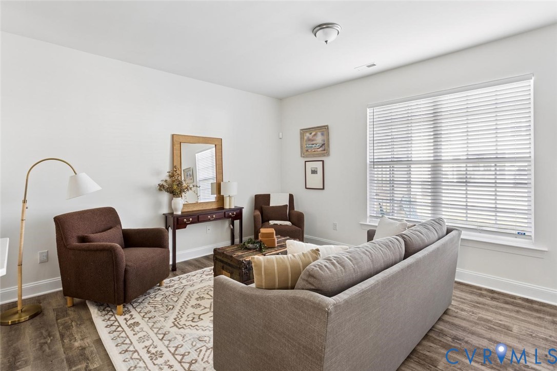 Spacious room featuring LVP flooring, crisp white walls, and a large windows with blinds.