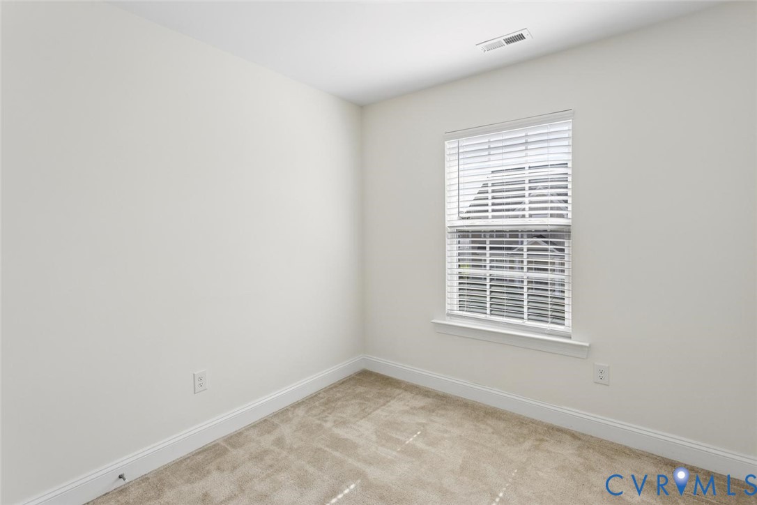 Neutral-toned carpeting, white painted walls, and a window with blinds.