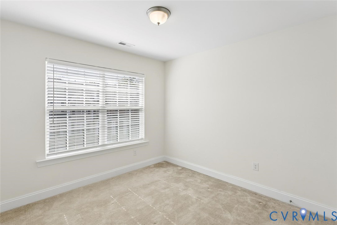 Neutral wall finishes, window with blinds, carpet flooring, overhead flush-mount light fixture.