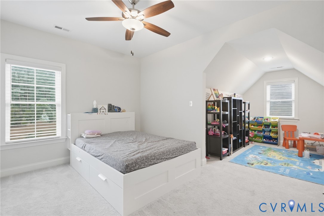Vaulted ceilings, neutral carpeting, multi-pane windows, and a central ceiling fan with integrated lighting