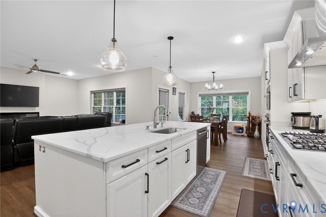 Kitchen featuring a central island with a solid-surface countertop, white cabinetry with matte black hardware, recessed lighting, and wood-finish flooring