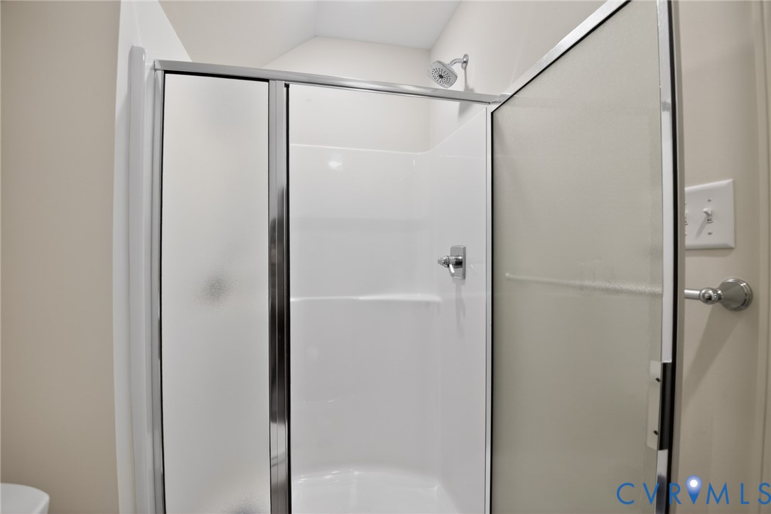 Shower stall featuring a white acrylic surround, chrome fixtures, and a glass door with a metal frame