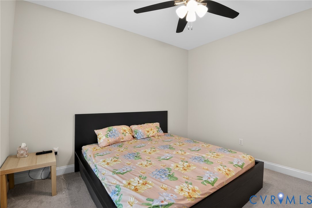 Neutral-toned interior space featuring wall-to-wall carpeting and a ceiling-mounted fan with integrated multi-bulb lighting
