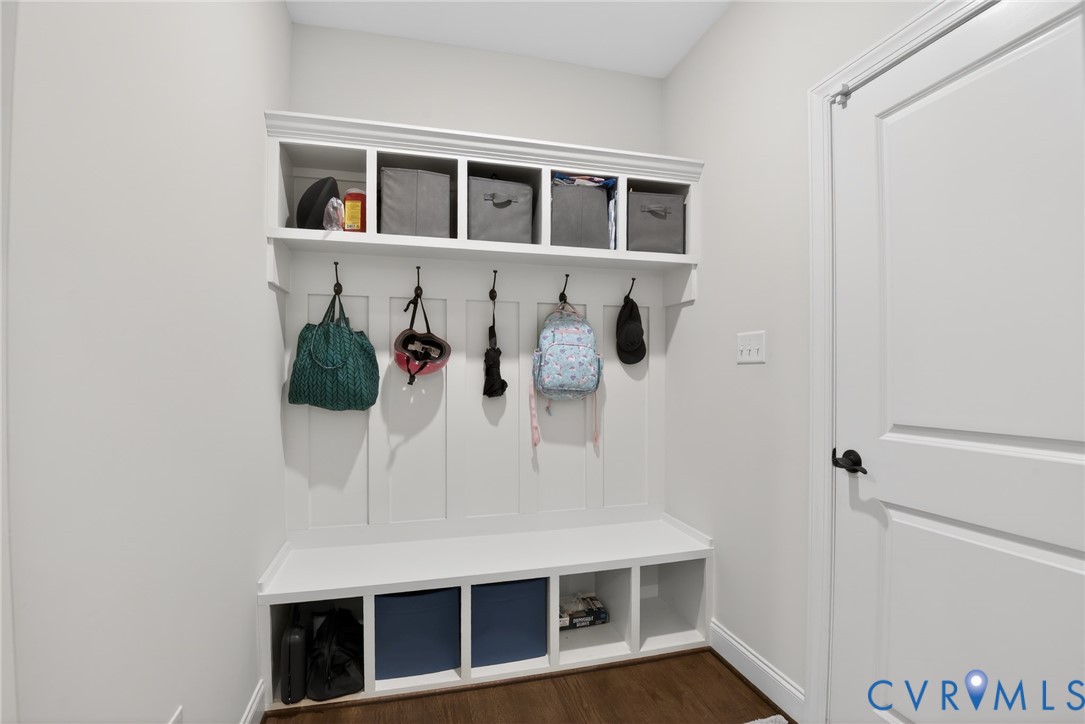 Built-in cabinetry featuring white board-and-batten millwork, integrated upper and lower cubby storage, and wall-mounted hooks