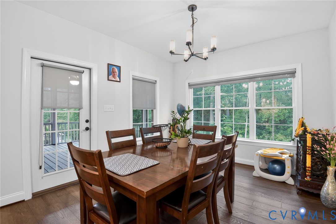 Dining area featuring wood-finish flooring, a multi-light chandelier, and large windows with multi-pane glass