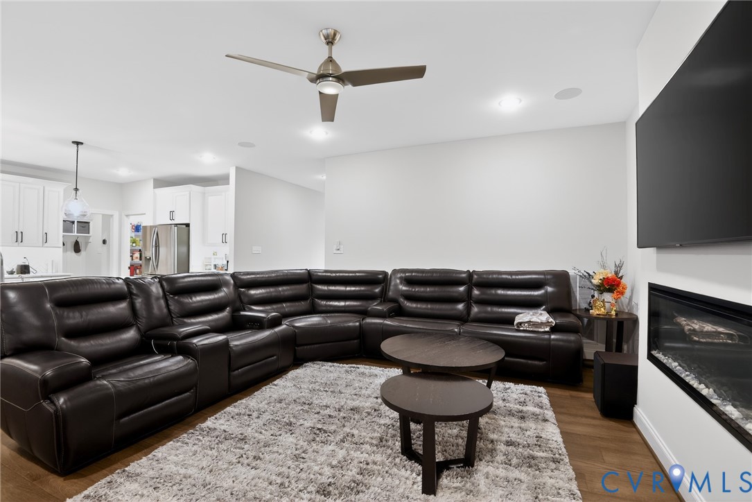 Living area featuring recessed lighting, a ceiling fan, wood-finish flooring, and a wall-mounted horizontal fireplace