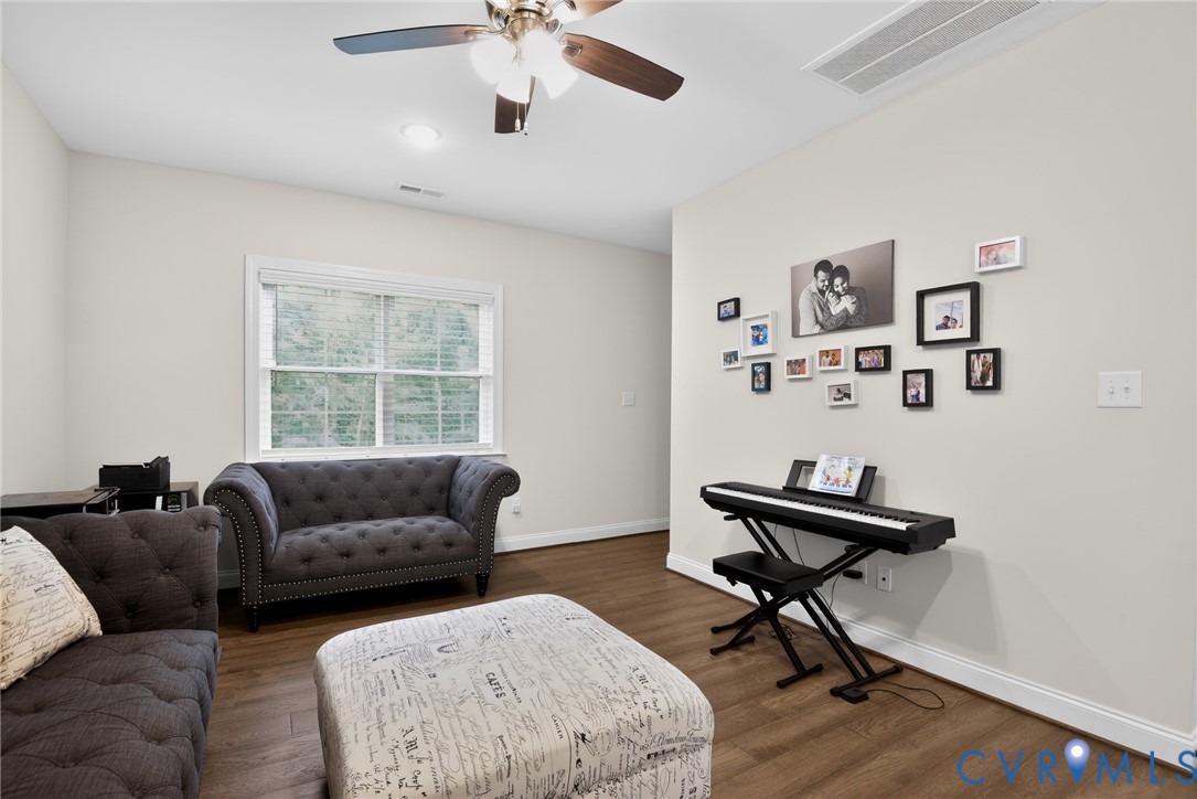 Neutral-toned walls, wood-finish flooring, multi-pane window, and ceiling-mounted fan with integrated lighting