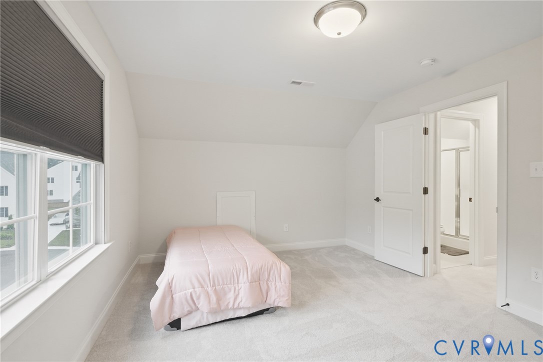 Room featuring neutral carpet, sloped ceilings, a multi-pane window with a fitted shade, and a flush-mount ceiling light fixture