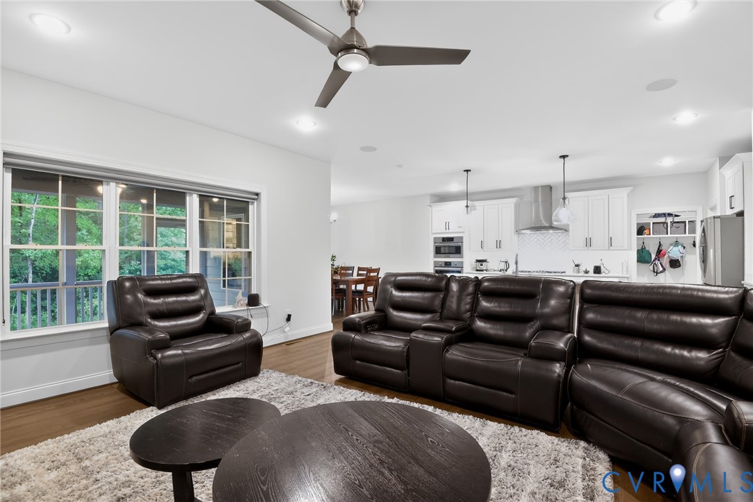 Open concept living area featuring wood-finish flooring, recessed lighting, ceiling fan, and multi-pane windows