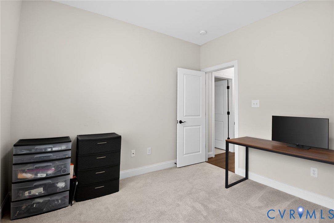Neutral-toned walls, wall-to-wall carpeting, and a two-panel interior door with matte black hardware