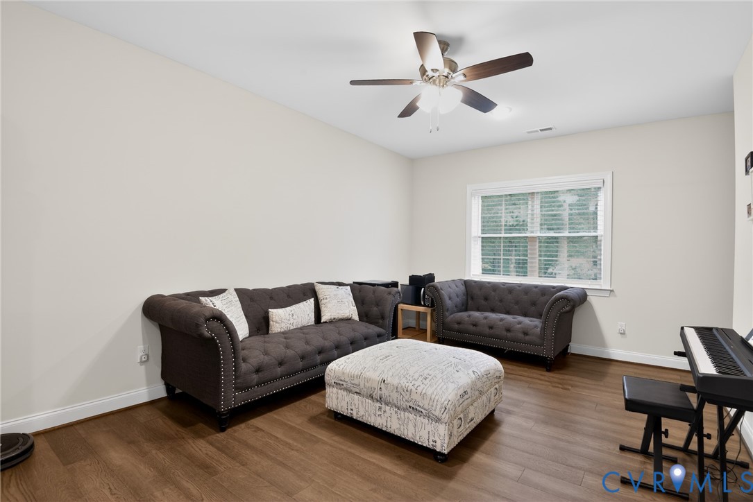 Wood-finish flooring, neutral wall tones, multi-pane window, and a central ceiling fan with integrated lighting